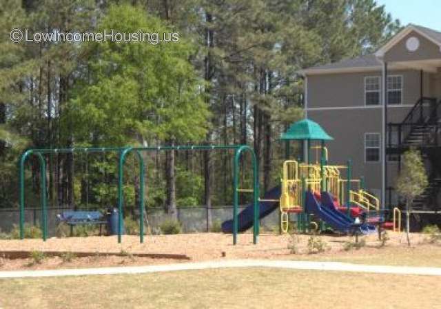 This is a photograph of a child's play area.  There are sliding boards, a trampoline, and a structure for swinging hand over hand to get to a trampoline 