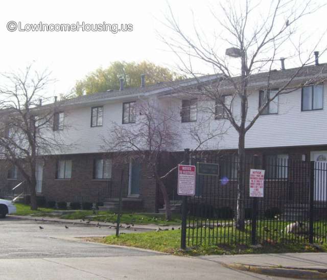 Town houses built on brick foundation and topped with white clapboard finish.  There appear to be 4 rooms on the upper level per unit