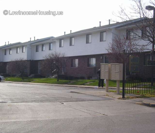 Row housing consisting of lower level brick structure with white clapboard enclosure above.  Each unit has 4 windows on the upper level facing the street.