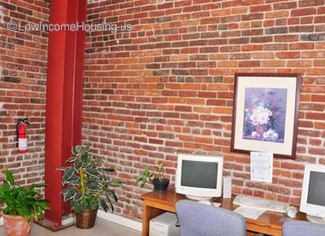 Interior view of spacious office with tasteful exposed bright red brick walls, steel columns frame work space. 