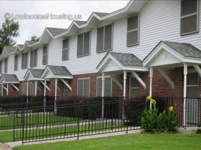 Solid brick first floor construction with wrought iron fencing, white clapboard dormer units with ample windows installed. 