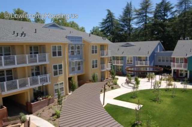 Three level residential living spaces served by large covered walkway.  Facility contains 4 three story building units - light brown and green.  