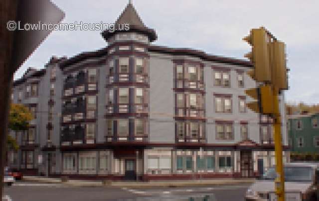Large, four story apartment building occupying city block.  Commercial shops on ground floor, residential space on second, third and fourth floors. Street parking available. 